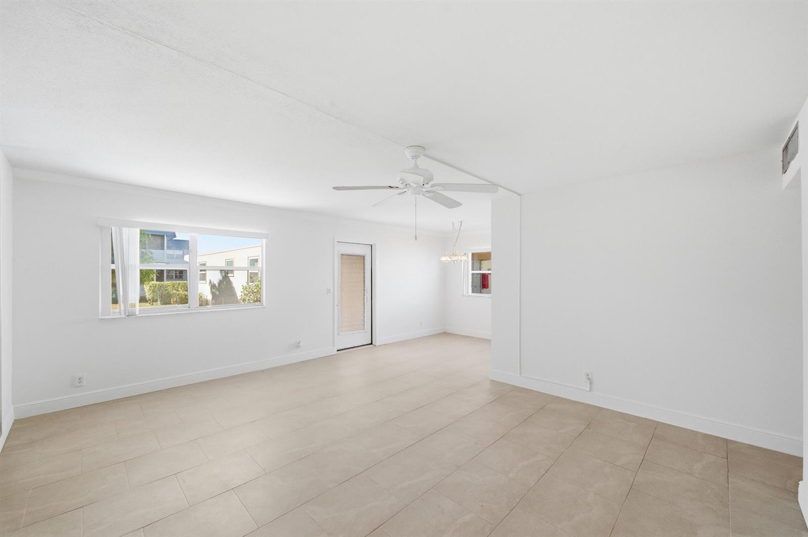 An empty room with white walls, tile flooring, a ceiling fan, and a glass door — 452 Brittany J, Delray Beach FL 33446, DELRAY BEACH, FL