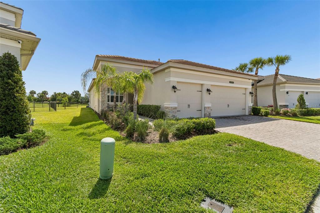 A single-story house with a two-car garage, stone accents, and a landscaped front yard — 32732 TREE OF LIFE AVENUE, WESLEY CHAPEL, FL
