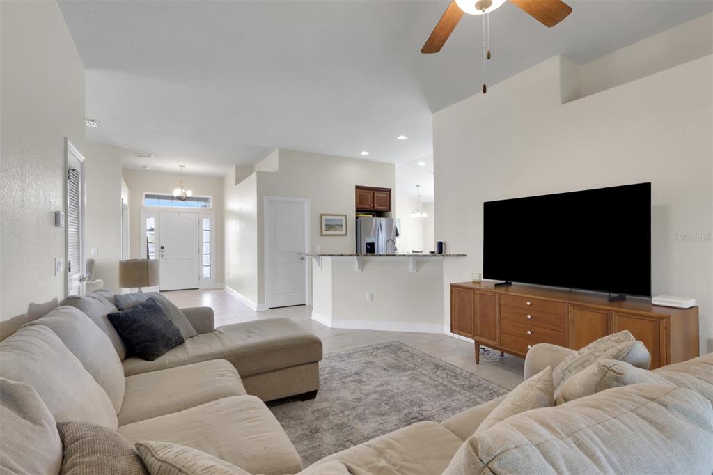 A living room features a sectional sofa, a television on a wooden console, and tile flooring — 27077 BROOK FOREST ROAD, PUNTA GORDA, FL