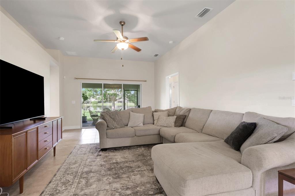 A living room features a large sectional sofa, a television console, and sliding glass doors — 27077 BROOK FOREST ROAD, PUNTA GORDA, FL