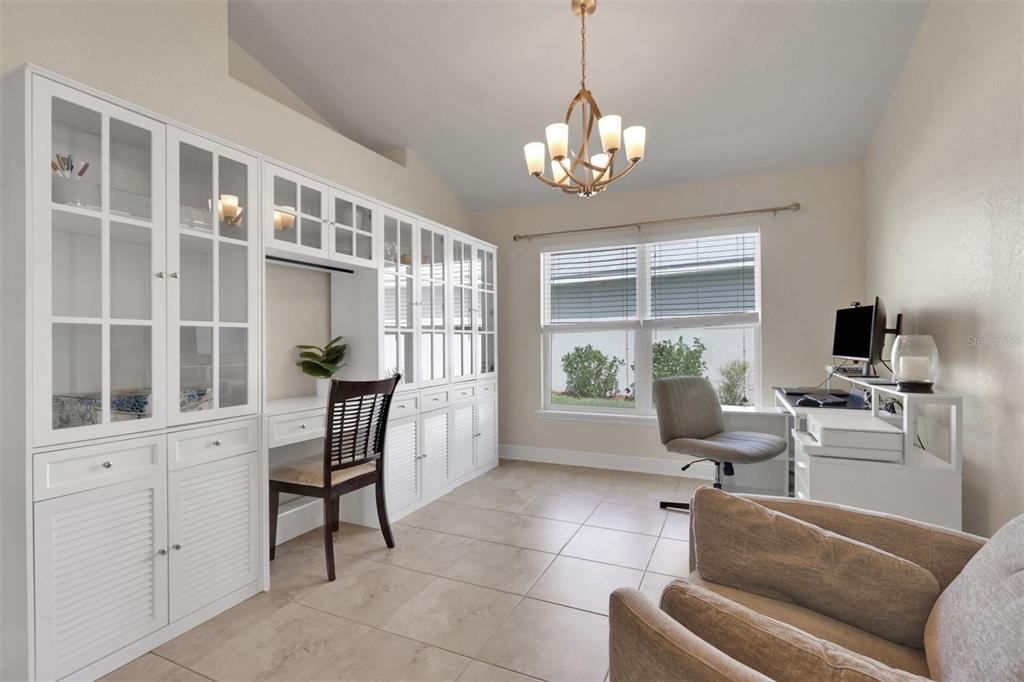 A home office features white built-in cabinetry, a desk, a window, and tile flooring — 27077 BROOK FOREST ROAD, PUNTA GORDA, FL