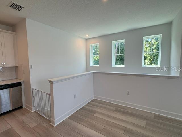 A bright room with light wood-look flooring, white walls, three windows, and a safety gate — 7573 ESTUARY LAKE LOOP UNIT B, CELEBRATION, FL