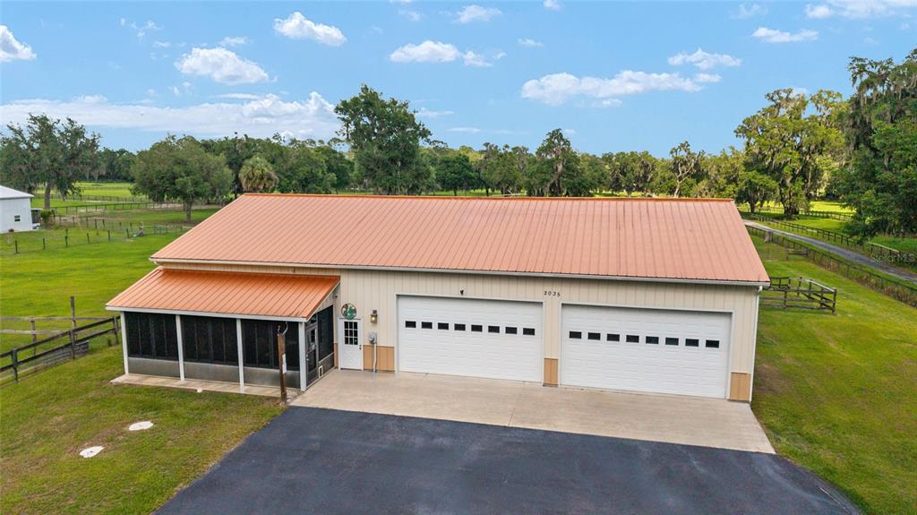 An exterior view of a metal-roofed building with a screened porch and two garage doors — 2035 NW 150TH AVENUE, OCALA, FL