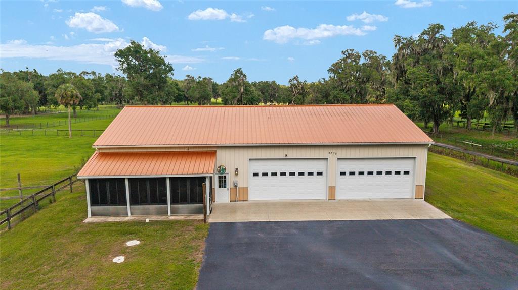 An exterior view of a metal-roofed building with two garage doors and a screened porch — 2035 NW 150TH AVENUE, OCALA, FL