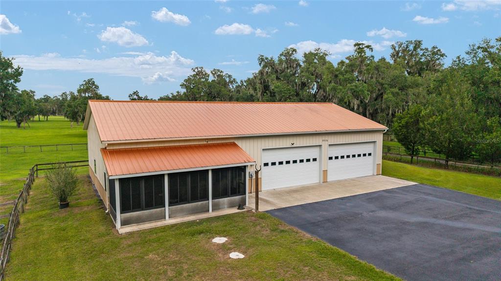 An aerial view of a metal-roofed building with a screened porch and two garage doors — 2035 NW 150TH AVENUE, OCALA, FL