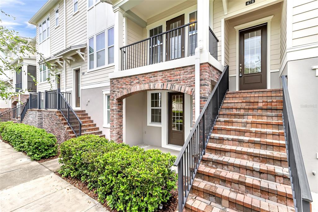 An exterior view of a multi-story townhouse with brick accents, a balcony, and front stairs — 474 WINDMILL PALM CIRCLE, ALTAMONTE SPRINGS, FL