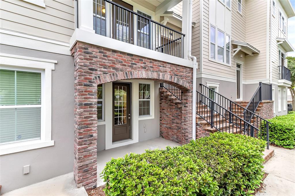 A ground-level brick arched entryway leads to a brown door beside an outdoor staircase — 474 WINDMILL PALM CIRCLE, ALTAMONTE SPRINGS, FL