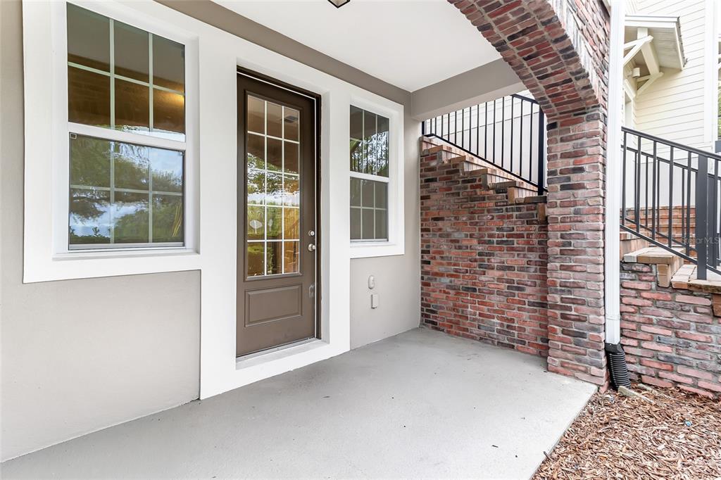 A covered patio features a glass-paneled door, a brick archway, and a brick staircase — 474 WINDMILL PALM CIRCLE, ALTAMONTE SPRINGS, FL