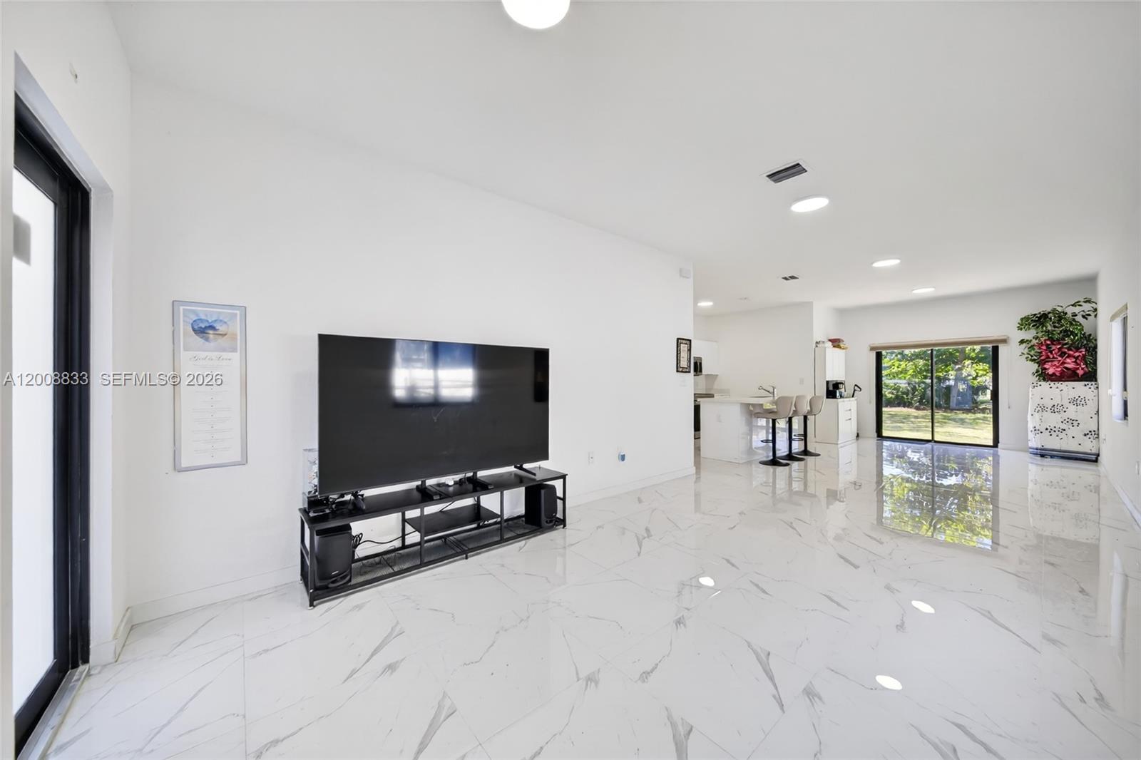 A bright, open-concept living area features white marble-look tile flooring and a modern kitchen — 1864 NW 84th St, Miami FL 33147, MIAMI, FL