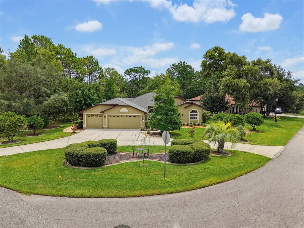 A single-story house with a three-car garage and a landscaped front yard — 1 PLUMBAGO DRIVE, HOMOSASSA, FL