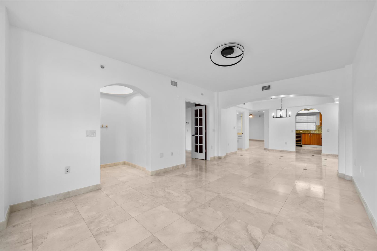 An open-concept living area with white walls, light tile flooring, and arched entryways — 2051 SE 3rd Street, Deerfield Beach FL 33441, DEERFIELD BEACH, FL