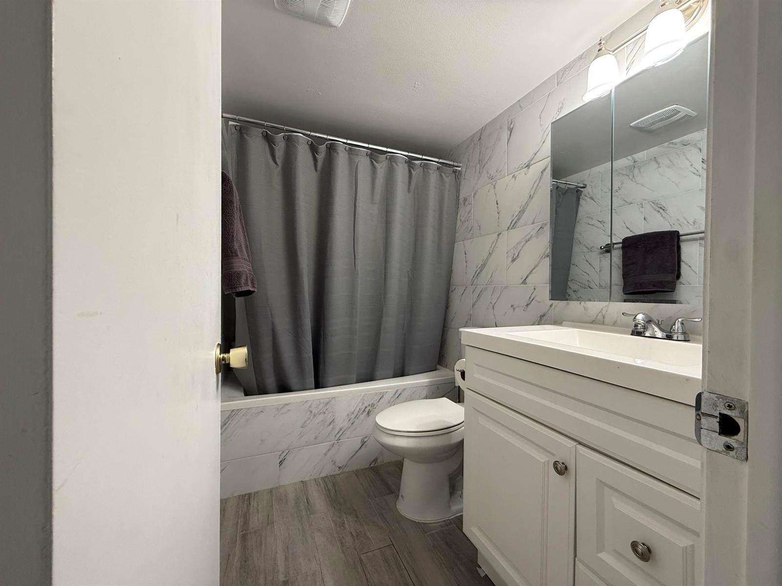 A bathroom features a white vanity, a toilet, and a shower-tub combo with marble-look tiles — 1040 SE 4th Avenue # 331, Deerfield Beach FL 33441, DEERFIELD BEACH, FL
