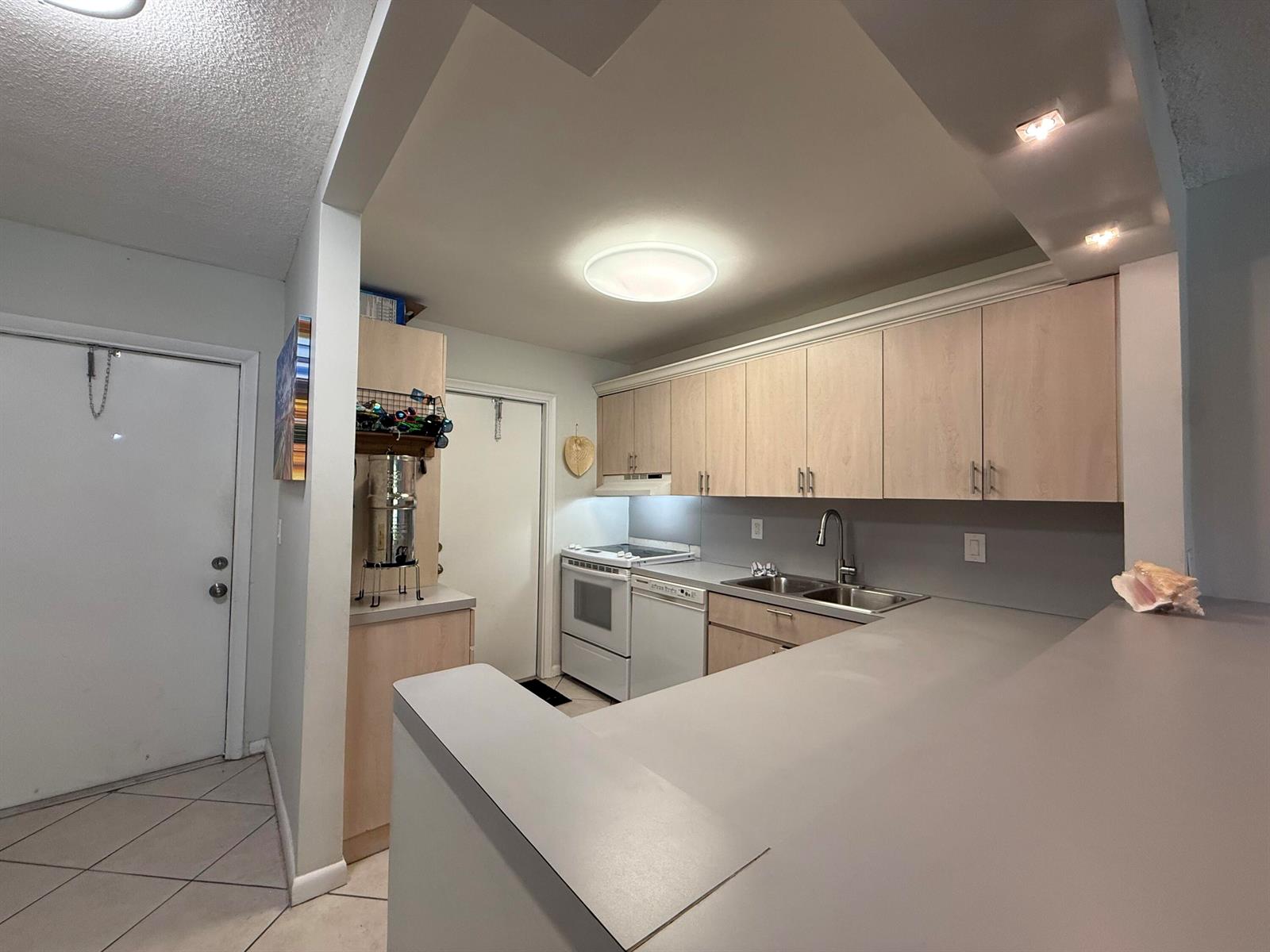 A kitchen features light wood cabinets, gray countertops, and white appliances — 1040 SE 4th Avenue # 331, Deerfield Beach FL 33441, DEERFIELD BEACH, FL