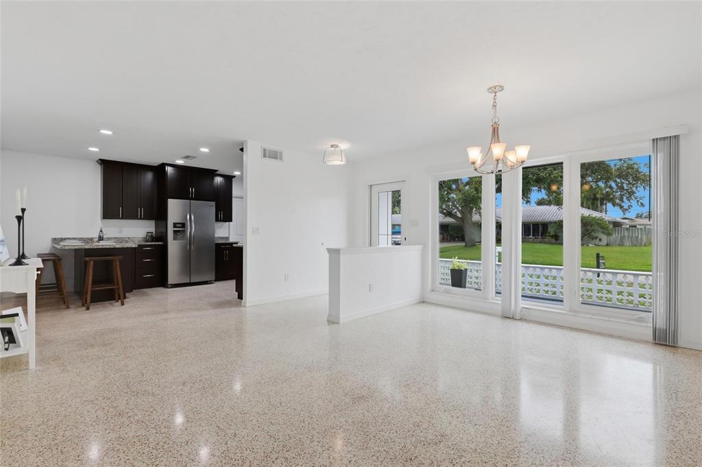 A bright, open-concept kitchen and dining area features dark cabinetry, terrazzo flooring, and large windows — 412 W SHADE DRIVE, VENICE, FL