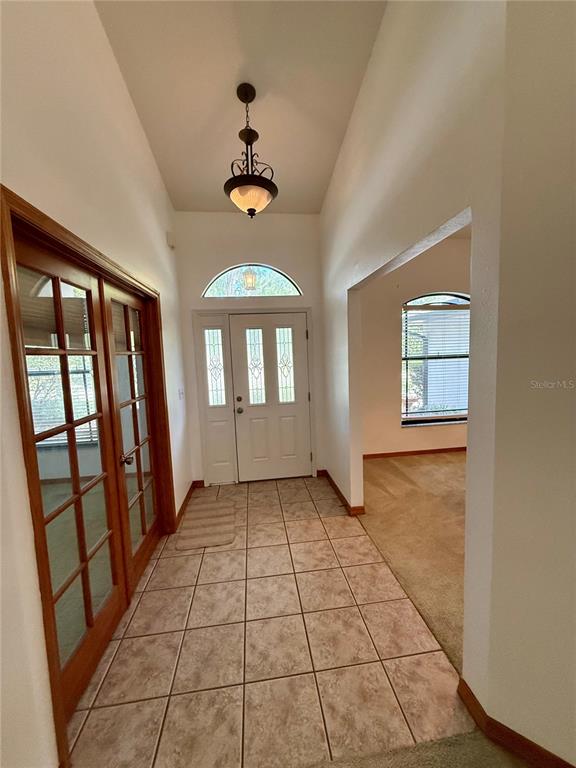 An entryway features tile flooring, a glass-paneled front door, and a hanging light fixture — 4843 CALASANS AVENUE, ST CLOUD, FL
