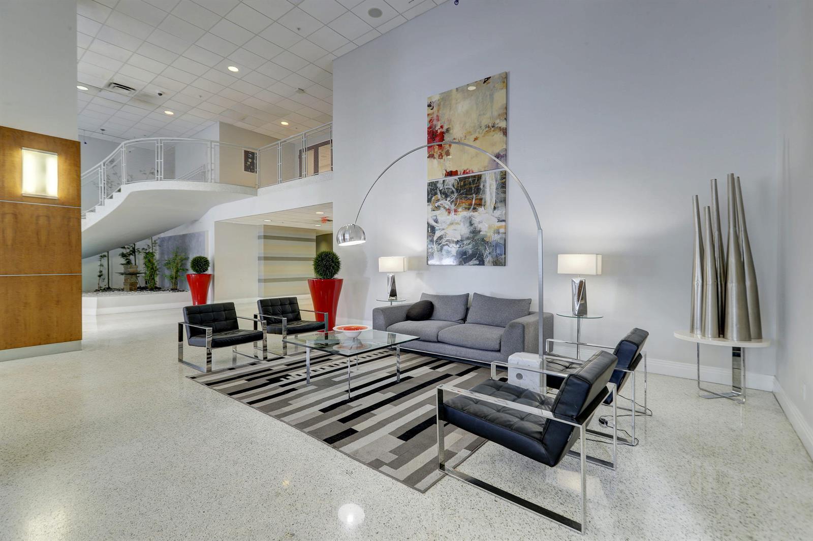 A modern lobby features a gray sofa, black leather armchairs, an area rug, and artwork — 3000 S Ocean Drive # 1100, Hollywood FL 33019, HOLLYWOOD, FL