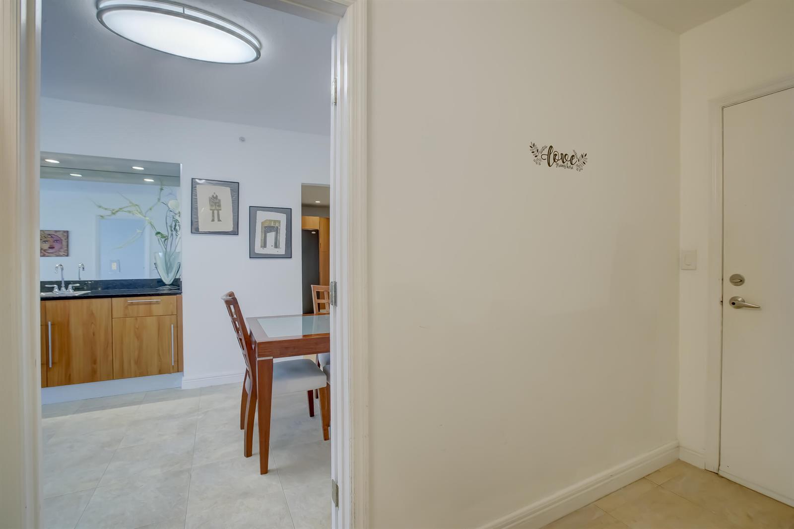 A view through a doorway shows a dining area with a wooden table and vanity — 3000 S Ocean Drive # 1100, Hollywood FL 33019, HOLLYWOOD, FL