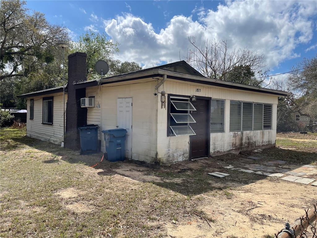 A single-story house with a brick chimney, light-colored siding, and a brown front door — 1813 ROBINSON DRIVE, HAINES CITY, FL