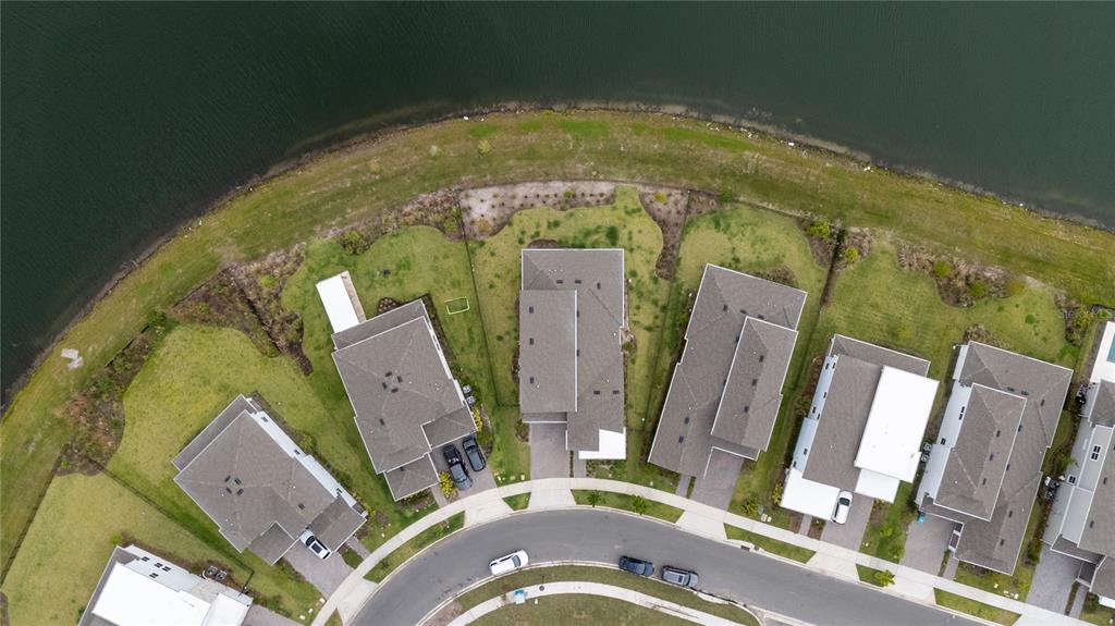 An aerial view shows a curved street lined with houses and backyards bordering a lake — 10044 BALLAST DRIVE, ORLANDO, FL