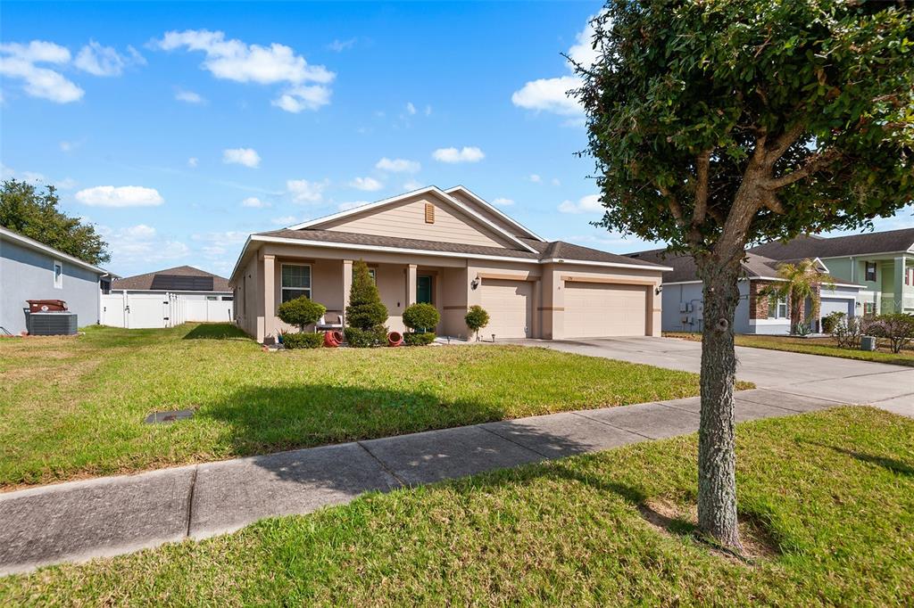A single-story suburban house with a tan exterior, a two-car garage, and a front lawn — 236 BARRINGTON DRIVE, HAINES CITY, FL
