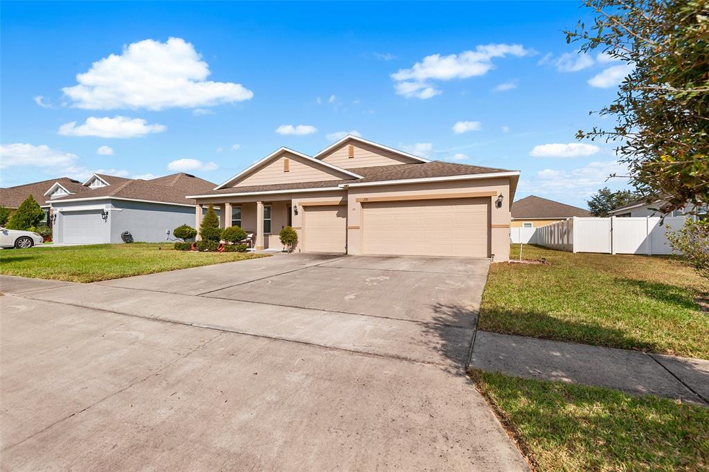 A tan single-story house with a three-car garage and a concrete driveway — 236 BARRINGTON DRIVE, HAINES CITY, FL