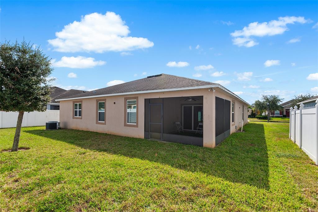 The exterior of a tan house features a screened-in back porch and a grassy yard — 236 BARRINGTON DRIVE, HAINES CITY, FL