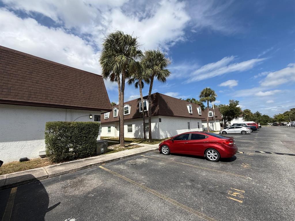 A red sedan is parked in a lot in front of two-story apartment buildings — 9002 TUDOR DRIVE UNIT K201, TAMPA, FL