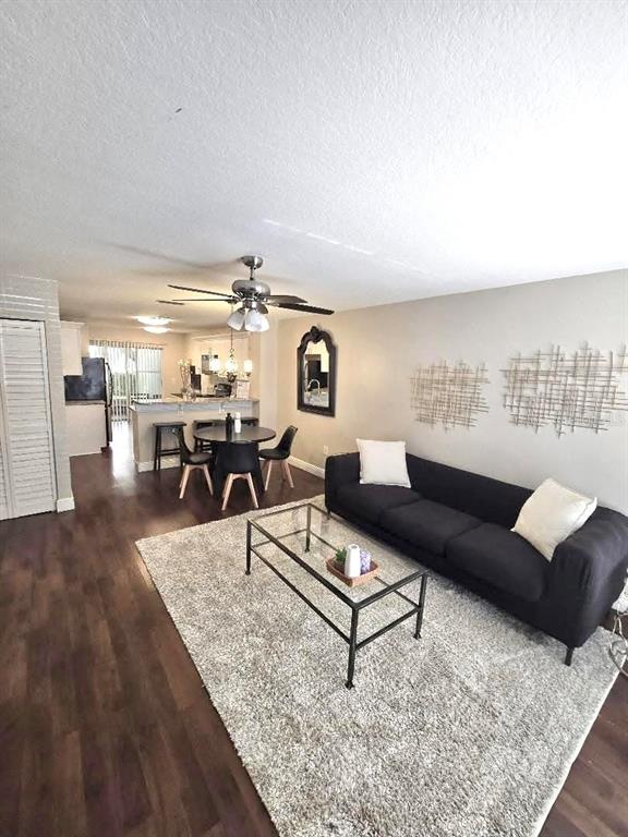 A living room features dark wood flooring, a black sofa, and an adjacent dining area — 7910 HARDWICK DRIVE UNIT 713, NEW PORT RICHEY, FL