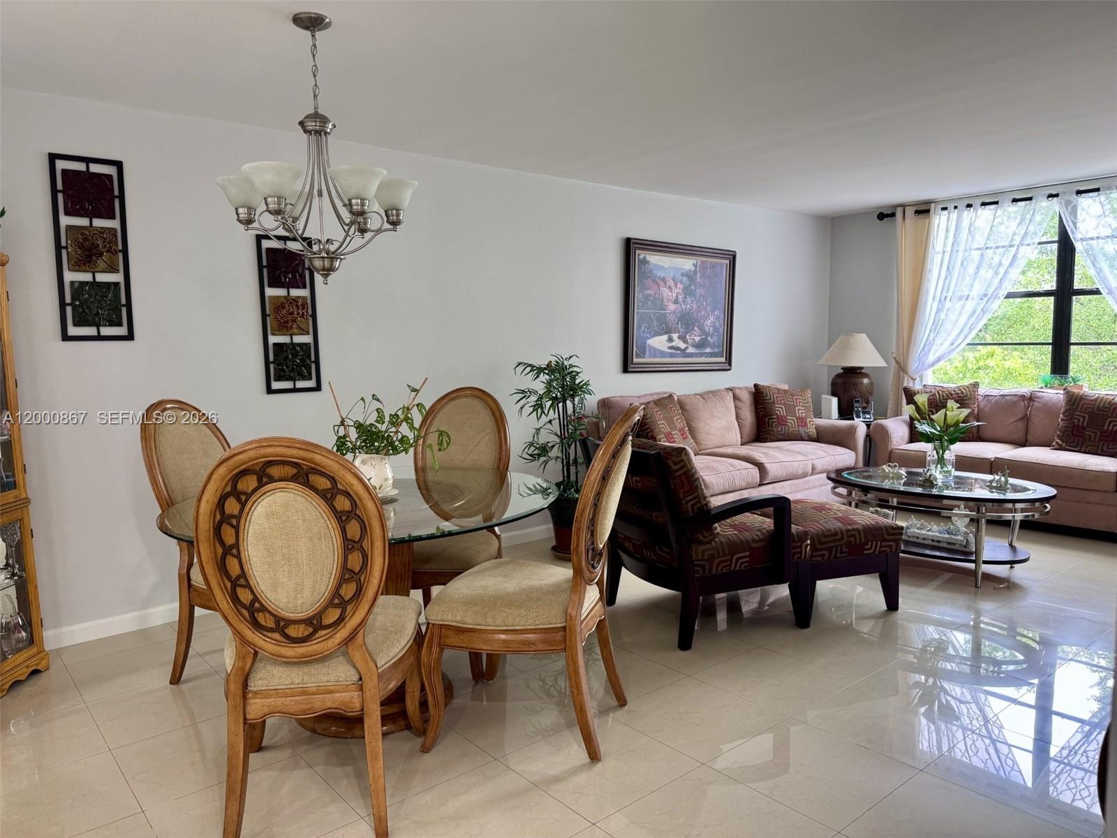 A dining area with a glass table and chairs sits adjacent to a living room — 10850 N Kendall Dr # 414, Miami FL 33176, MIAMI, FL