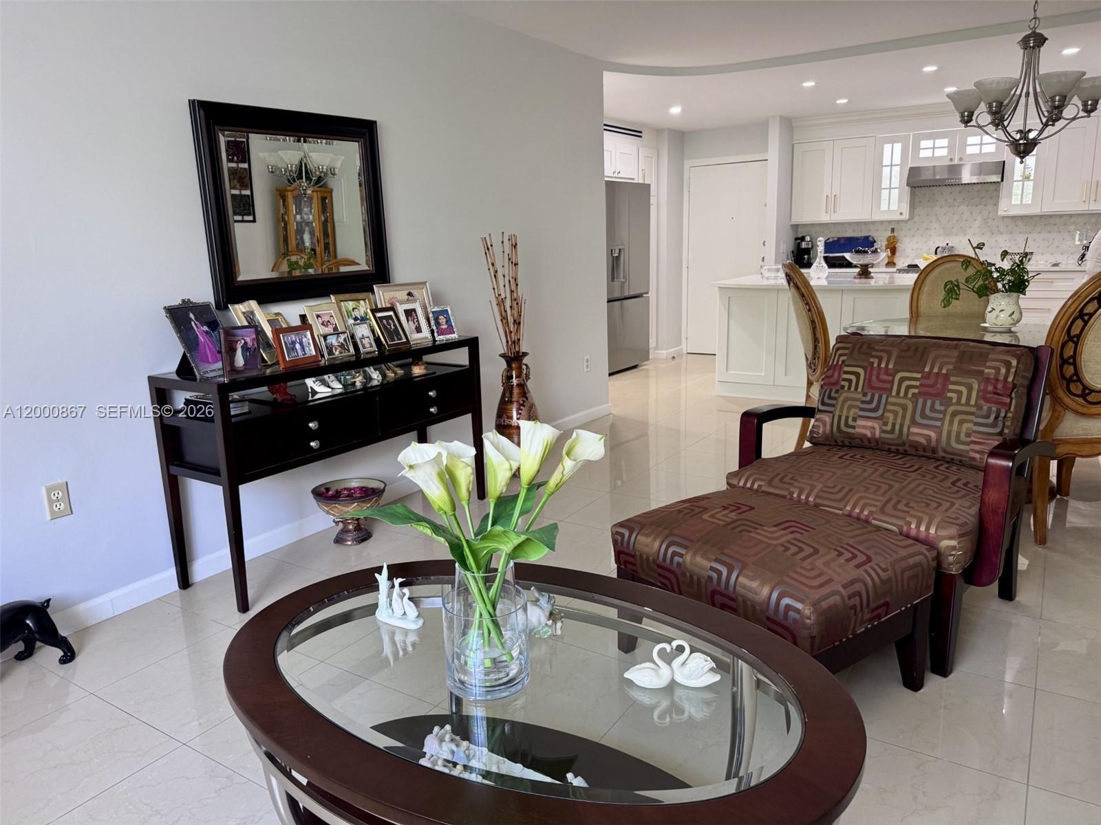 A living room with a glass-topped coffee table, patterned chaise lounge, and a dark wood console — 10850 N Kendall Dr # 414, Miami FL 33176, MIAMI, FL