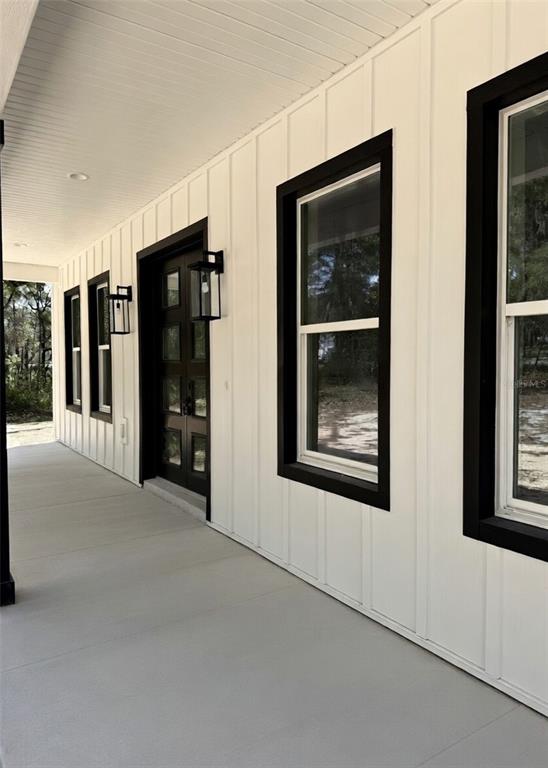 A covered porch features white board-and-batten siding, black window frames, and a dark front door — 2207 COUNTY ROAD 243E, WILDWOOD, FL