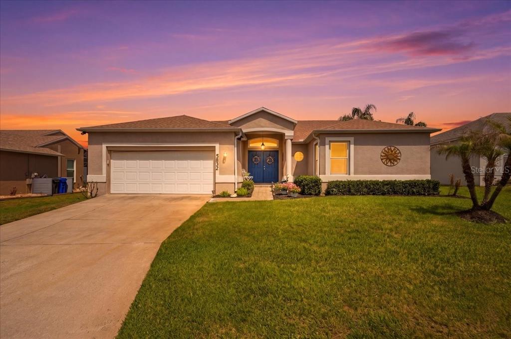 A single-story suburban house with a two-car garage, blue front door, and manicured lawn — 5832 SWALLOW DRIVE, LAKELAND, FL