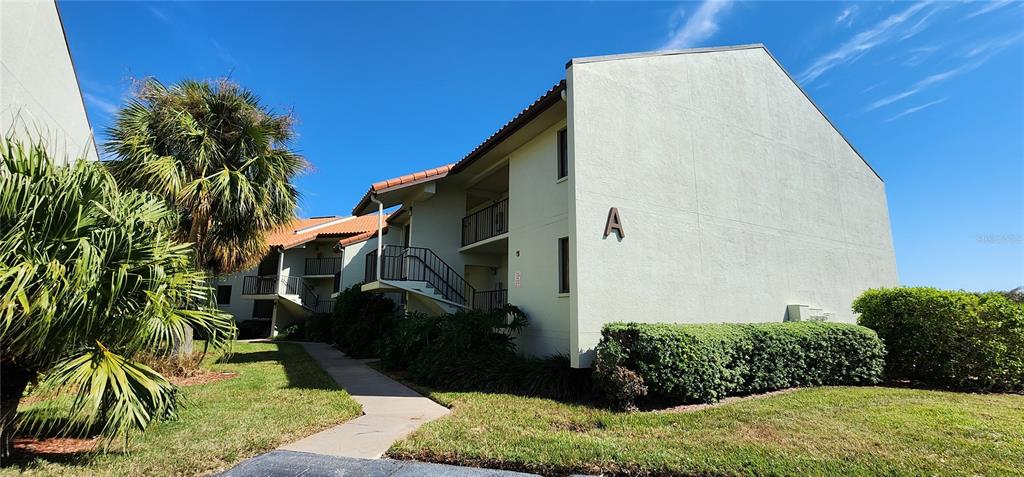 A multi-story apartment building with a light-colored exterior and a palm tree in front — 1515 PINELLAS BAYWAY S UNIT 8, TIERRA VERDE, FL