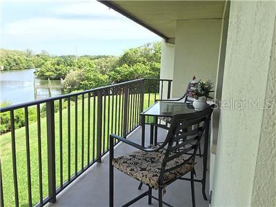 A balcony with a metal railing overlooks a grassy lawn and a body of water — 1515 PINELLAS BAYWAY S UNIT 8, TIERRA VERDE, FL