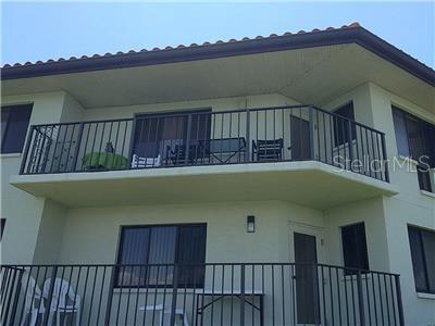 A two-story building exterior features balconies with black metal railings and light green stucco walls — 1515 PINELLAS BAYWAY S UNIT 8, TIERRA VERDE, FL