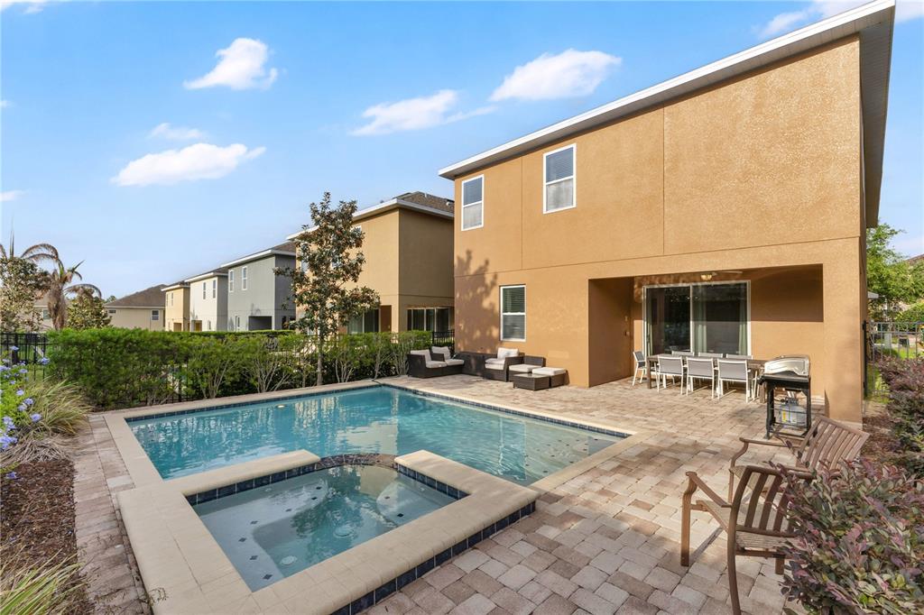 A two-story house exterior features a backyard swimming pool, spa, and a paved patio area — 410 NOVI PATH, KISSIMMEE, FL