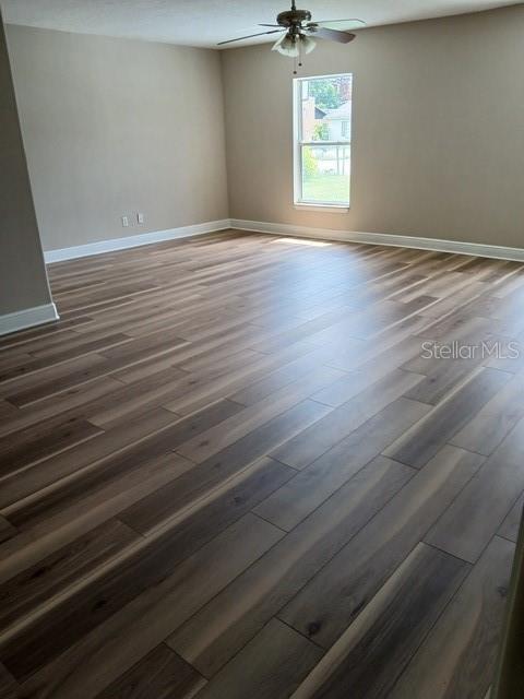 An empty room features light-colored walls, a ceiling fan, and dark wood-look plank flooring — 3808 CYPRESS AVENUE, SANFORD, FL