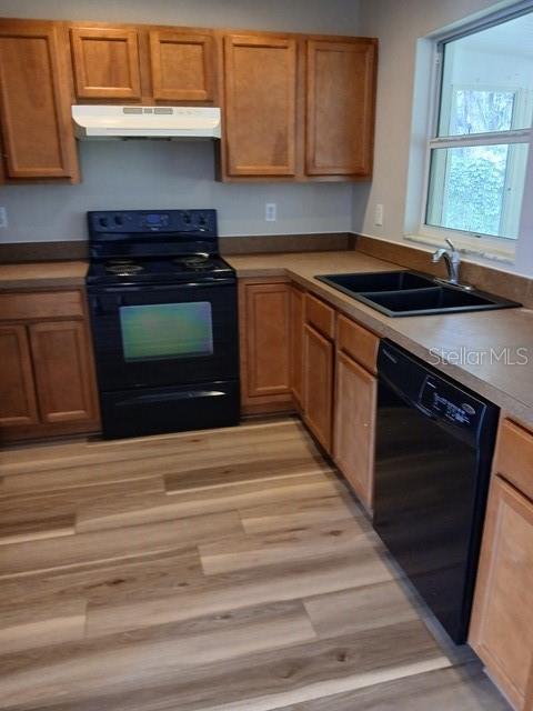 A kitchen features wood cabinets, black appliances, a double sink, and light-colored wood-look flooring — 3808 CYPRESS AVENUE, SANFORD, FL