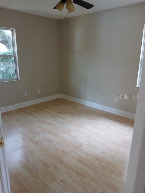 An empty bedroom features light-colored wood-look flooring, beige walls, and a ceiling fan — 3808 CYPRESS AVENUE, SANFORD, FL