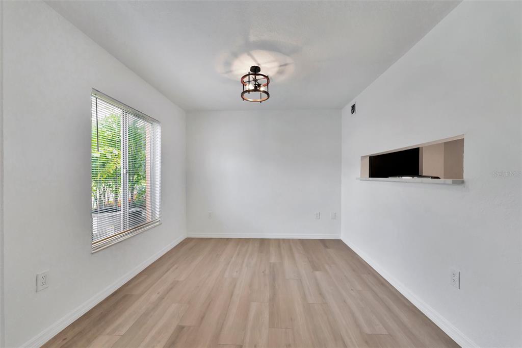 An empty room features light wood-look flooring, white walls, a window, and a ceiling light — 9940 7TH WAY N UNIT 101, ST PETERSBURG, FL