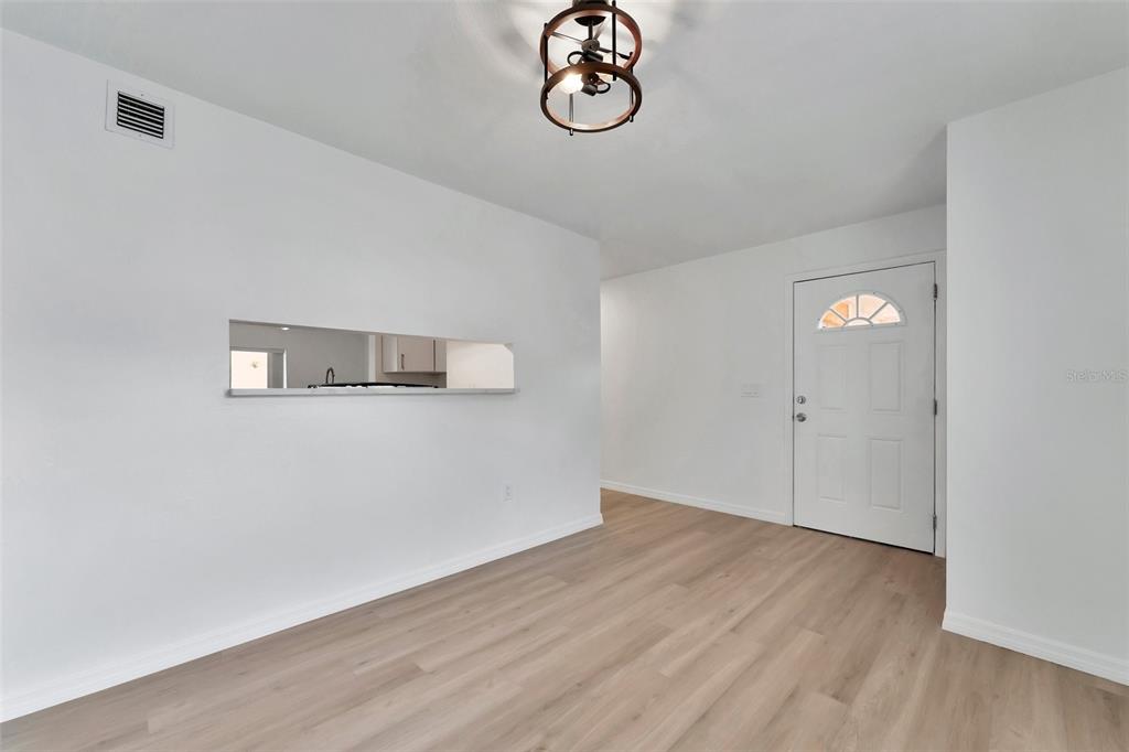 An interior view of a room with white walls, light wood flooring, and a pass-through window — 9940 7TH WAY N UNIT 101, ST PETERSBURG, FL