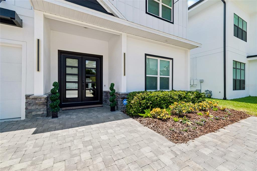 A modern white house exterior features a double front door, stone accents, and paved driveway — 4022 W BAY TO BAY BOULEVARD, TAMPA, FL