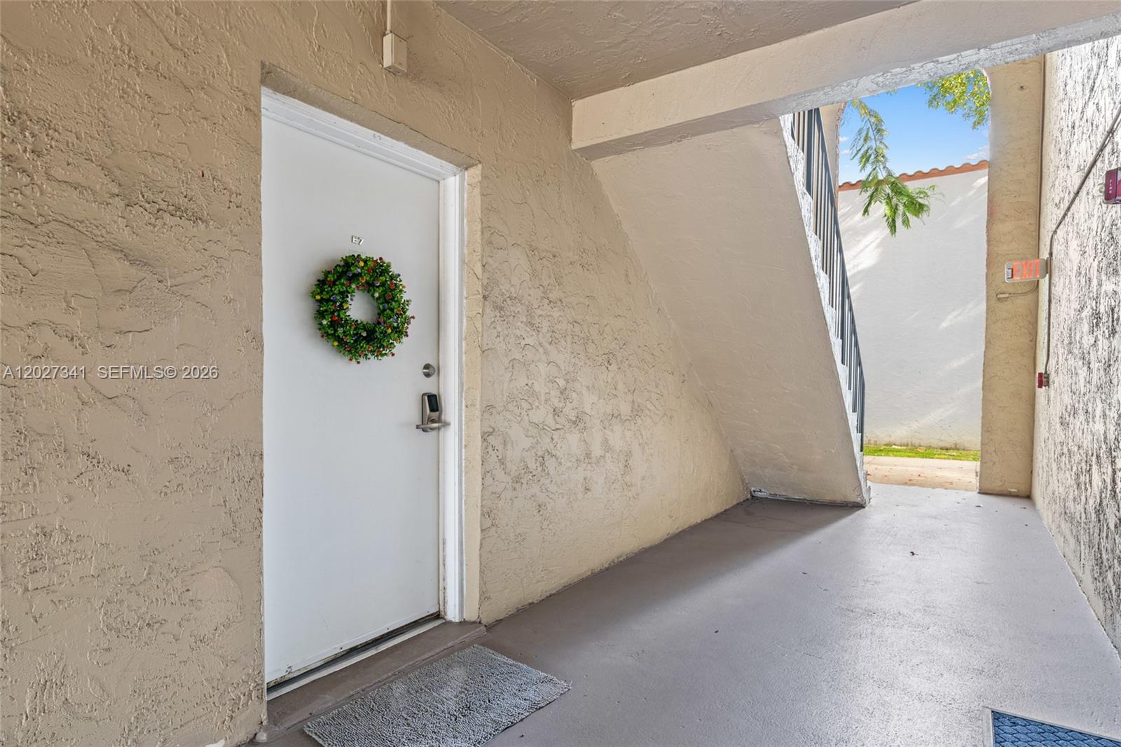 An exterior view shows a white apartment door with a wreath under a staircase — 10780 N Kendall Dr # E7, Miami FL 33176, MIAMI, FL