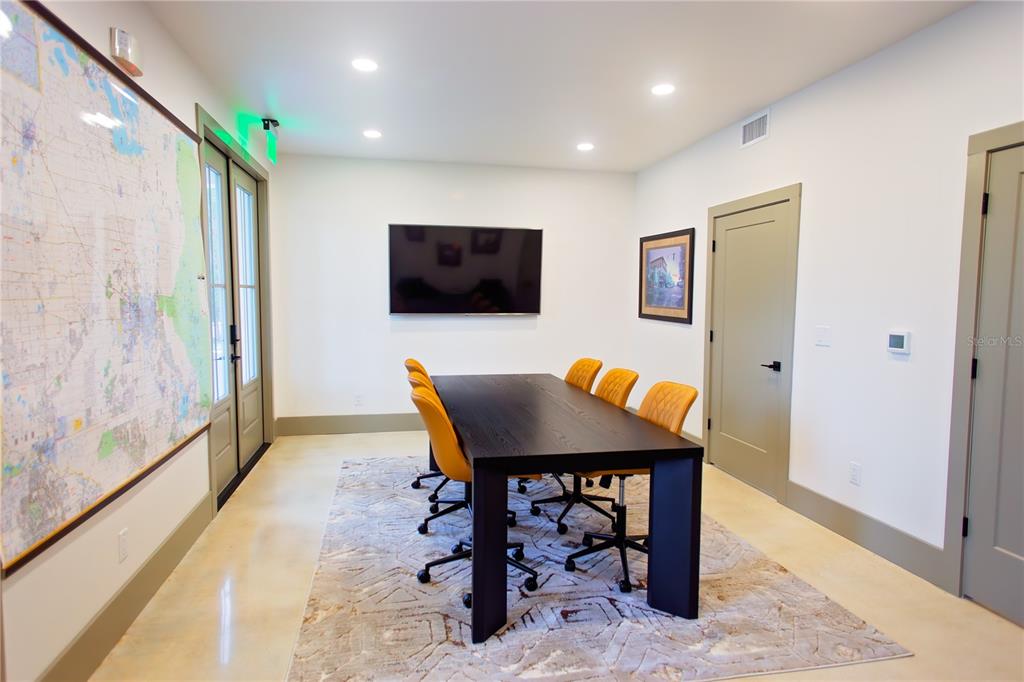 A conference room features a dark wood table, yellow chairs, a wall-mounted television, and map — 521 SE 2ND STREET, OCALA, FL