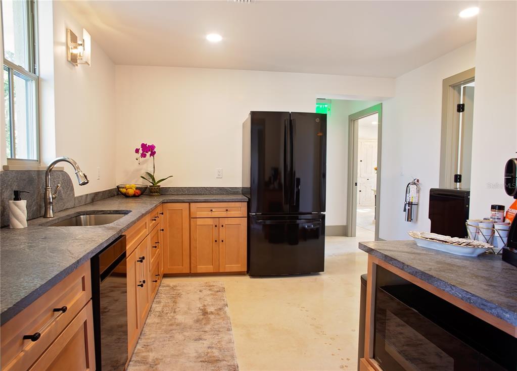 A kitchen features light wood cabinets, dark gray countertops, and a black refrigerator — 521 SE 2ND STREET, OCALA, FL