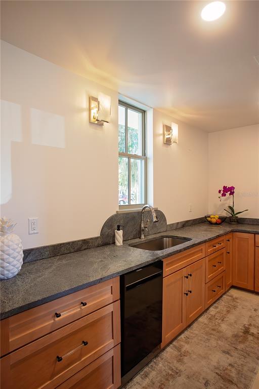 A kitchen features light wood cabinets, dark stone countertops, a sink, and a window — 521 SE 2ND STREET, OCALA, FL