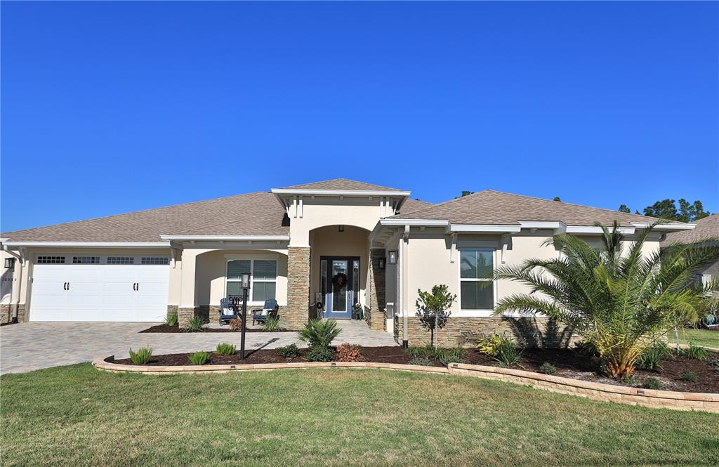 A single-story house with a beige stucco exterior, stone accents, and a two-car garage — 10555 SW 96TH LANE ROAD, OCALA, FL
