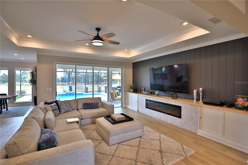 A living room features a sectional sofa, a fireplace, and sliding doors overlooking a pool — 10555 SW 96TH LANE ROAD, OCALA, FL