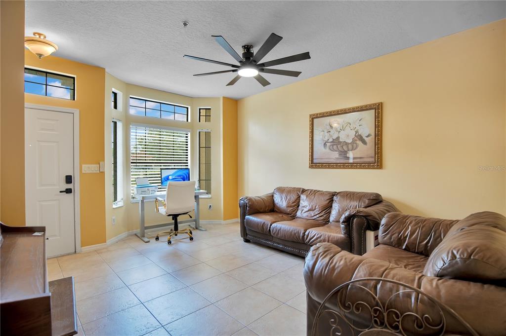 A living room with tile floors, yellow walls, a ceiling fan, and a desk area — 6007 SCOTCHWOOD GLEN UNIT 39, ORLANDO, FL