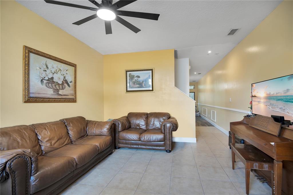 A living room features yellow walls, tile flooring, leather furniture, and a ceiling fan — 6007 SCOTCHWOOD GLEN UNIT 39, ORLANDO, FL